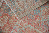 Distressed vintage Karaja carpet folded, revealing red, blue geometric motifs, exposed foundation.