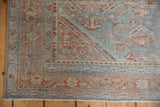 Corner detail of a distressed Mahal rug with geometric patterns in powder blue and muted ruby red.