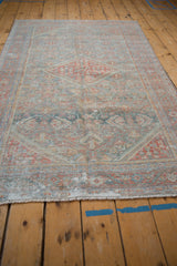 A distressed Persian Mahal rug viewed from a low angle, emphasizing its length and softened geometric pattern.