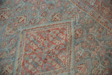 A corner detail of the distressed Mahal rug's ruby red medallion and powder blue floral field.
