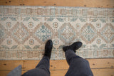 Distressed vintage Northwest Persian runner with repeating ivory, blue, and brown medallions.