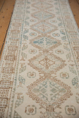 Distressed vintage Northwest Persian runner's low pile, geometric ivory, coffee, and dusty blue pattern.
