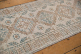 Repeating geometric medallions and hook and latch motifs in faded coffee brown and dusty denim blue.
