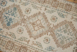 Distressed vintage Persian runner featuring faded ivory, dusty blue, and coffee brown geometric motifs.