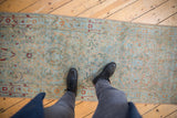 A viewpoint looking down at the distressed pile and floral pattern of a Sarouk runner.