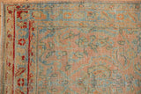 The evenly worn pile of a distressed Sarouk runner's corner, with a red floral border and blush field.
