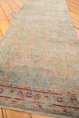 Angled view of a distressed Sarouk runner showing its length, low-pile texture, and dusty blush and powder blue colors.