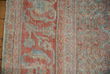 Close-up of distressed Mahal rug's worn pile, showing terracotta and powder blue Herati motif.