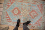 Faded powder blue and pale cherry red geometric medallions on a distressed Caucasian rug.