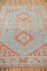 Faded powder blue and pale cherry red geometric medallions on a distressed Caucasian rug.