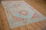 Distressed vintage Caucasian rug with intact side selvage and geometric hook motifs.