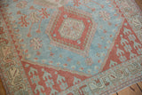 Distressed Caucasian rug, highlighting pale cherry red geometric motifs and softened texture.