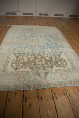 Distressed vintage Malayer rug with visible wear, coffee brown plant finials, and powder blue tones.