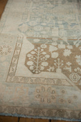 Decorative distressed Malayer rug showing worn coffee brown plant motifs on a pale powder blue field.