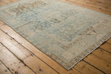 Distressed Malayer rug corner, revealing worn pile texture in powder blue, ivory, and coffee brown.
