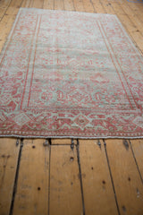 Angled view of a vintage Persian Mahal rug showing its low pile and repeating geometric medallions.