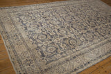Distressed Sparta rug corner showing worn dusty navy Herati motif and serrated border.