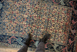 Distressed vintage Bijar rug's worn pile, showing geometric Herati design and abrashes.
