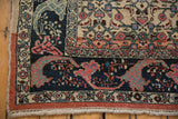 Distressed vintage Bijar rug corner, highlighting the curvilinear navy border with coral and blue florals.