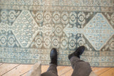 Faded, distressed Malayer runner with denim blue, charcoal, and beige Herati motifs underfoot.