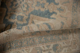 Folded distressed Karaja rug showing worn pile and faded beige-blue geometric pattern.