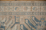 Distressed Karaja rug pile showing geometric border, stylized motifs in beige and denim blue.