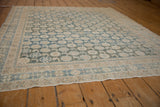 Distressed Mahal rug's corner with faded sky blue floral patterns, revealing worn texture.