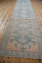 Distressed Malayer runner end, dusty blue, terracotta geometric motifs, showing even wear.
