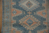 Close-up of vintage distressed Malayer runner showing dusty blue, terracotta geometric and vine motifs.