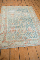 Vintage distressed Malayer rug with faded blue vinery and terracotta serrated border.
