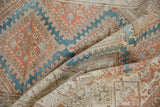 Folded vintage Malayer rug showcasing distressed texture, sky blue, and terracotta patterns.