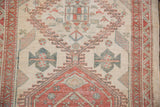 Close-up of the vintage Serab rug's geometric medallion and border in beige, red, and blue.
