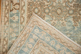 Distressed Hamadan rug runner's folded corner, showing its light blue and beige Herati pattern and hand-knotted back.