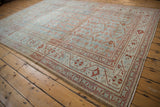 Vintage Persian Malayer rug shown at an angle, emphasizing its distressed texture and classic layout.