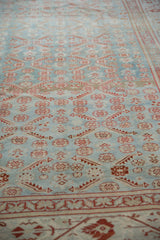 Angled view of the distressed Malayer's low pile and abrashed blue and red floral pattern.