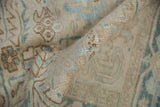 Textured pile of a distressed Mehrivan carpet with worn knots and muted beige-blue patterns.