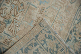 Folded corner of distressed Mehrivan carpet, showing worn geometric plants and blue Samovar Turtle border reverse.