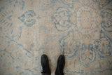Distressed Ahar carpet's faded ivory and dusty blue floral patterns, with boots.