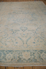 Distressed vintage Ahar carpet's ivory field, pale blue floral branches, and detailed border.