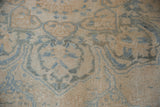 Distressed Ahar carpet texture, showing ivory and pale blue curvilinear patterns and knot heads.