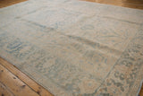 Distressed Ahar rug edge showing faded blue palmettes and ivory curvilinear motifs.