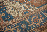 Sapphire blue and terracotta borders with detailed botanical motifs on an antique Serapi carpet.