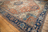 Antique Serapi carpet's navy border features detailed motifs alongside its terracotta field.