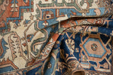 Antique Serapi carpet detail with folded pile, showing terracotta, sapphire blue, and ivory traditional motifs.