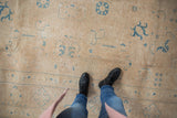 Distressed hand-knotted Sivas carpet showing even wear, faint sky blue motifs on a sand field.