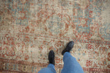 Worn foundation and distressed pile of antique Soumac carpet with faded sky blue and cherry red patterns.