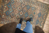 Antique Kurdish rug, geometric lattice, starburst borders, indigo blue, coffee brown, visible wear.