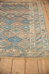 Repeating geometric lattice and starburst vine border on antique Kurdish rug, visible low pile.