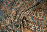 Antique Kurdish rug corner detail revealing geometric lattice field, vine border, visible wear.
