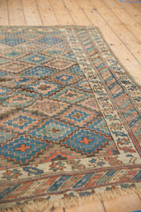 Antique Kurdish rug's geometric lattice design and vine border, indigo, brown, green with wear.